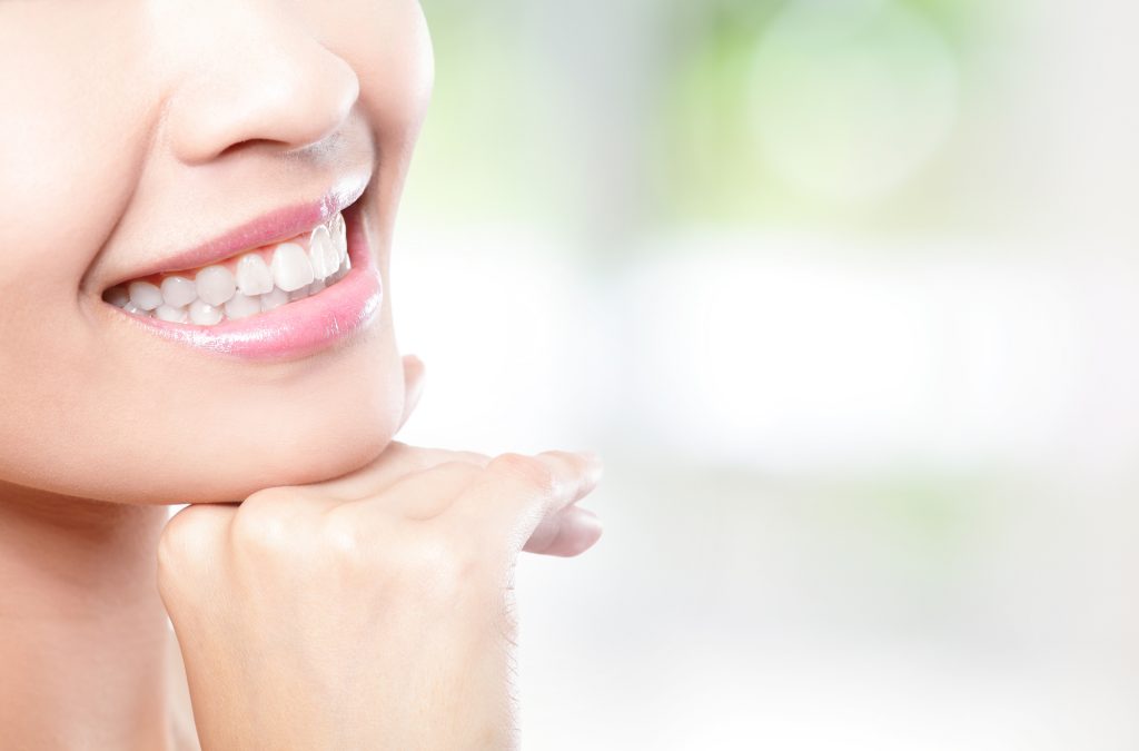 Beautiful young woman teeth close up with copy space on the right side. Isolated over green background, asian beauty model